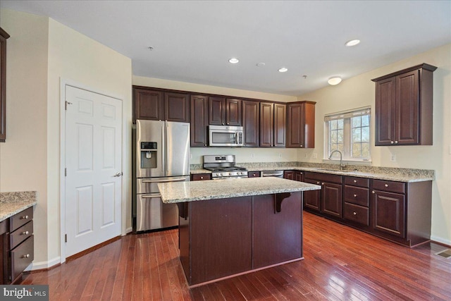 kitchen with sink, a breakfast bar area, a center island, appliances with stainless steel finishes, and light stone countertops