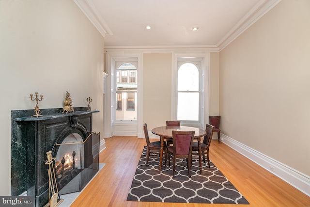 dining space featuring crown molding, a multi sided fireplace, and hardwood / wood-style flooring