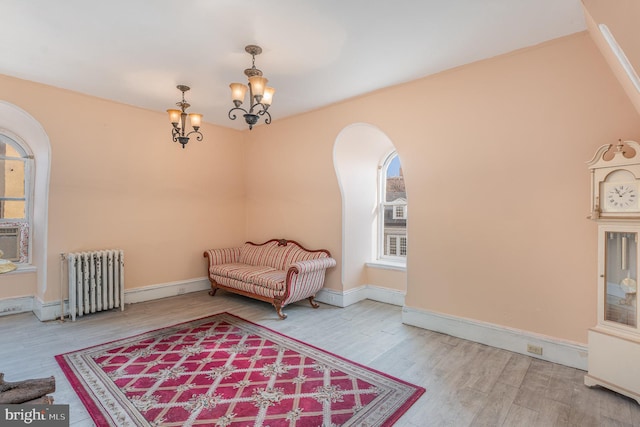 sitting room featuring a healthy amount of sunlight, hardwood / wood-style flooring, radiator heating unit, and a chandelier