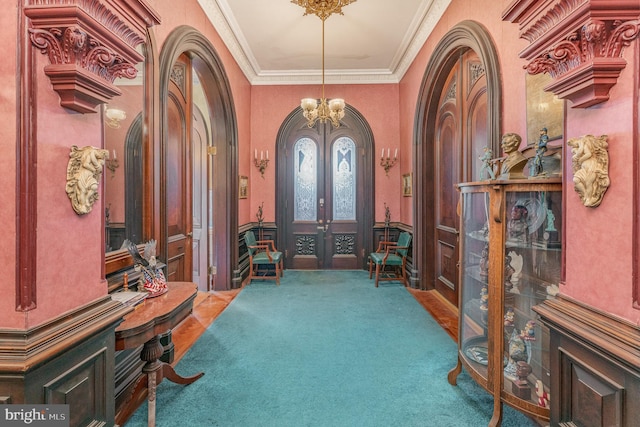 foyer with ornamental molding, french doors, a chandelier, and carpet flooring