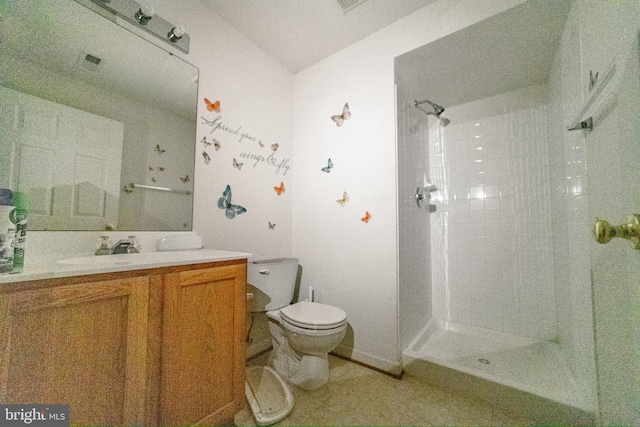 bathroom featuring tiled shower, vanity, and toilet