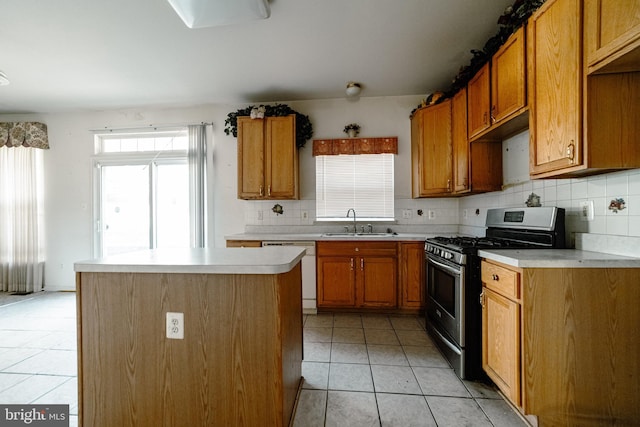 kitchen featuring sink, stainless steel gas range oven, plenty of natural light, white dishwasher, and a kitchen island