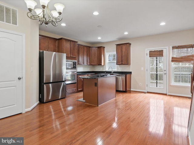 kitchen with sink, light hardwood / wood-style floors, a center island, and appliances with stainless steel finishes