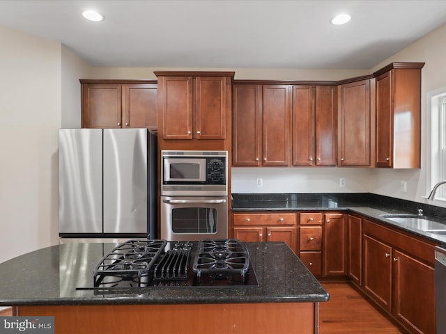 kitchen with sink, a center island, dark stone countertops, dark hardwood / wood-style floors, and stainless steel appliances