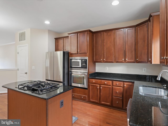 kitchen with dark stone countertops, sink, stainless steel appliances, and a center island