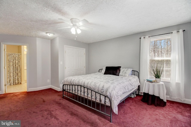 carpeted bedroom featuring ceiling fan, ensuite bathroom, a textured ceiling, and a closet