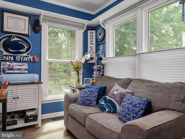 living area with crown molding, hardwood / wood-style floors, and a wealth of natural light