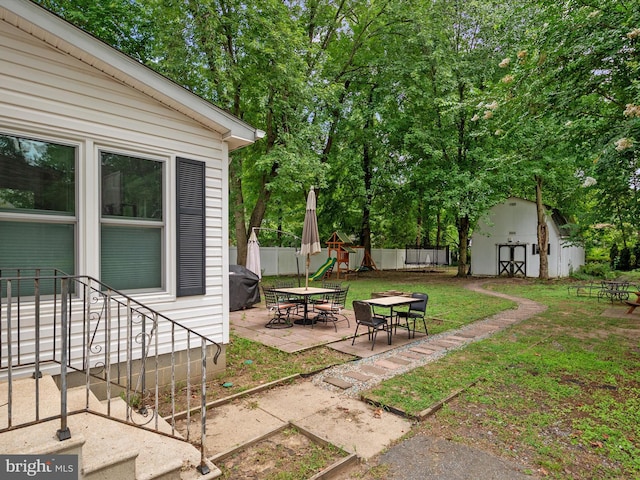 view of yard featuring a storage unit, a playground, and a patio