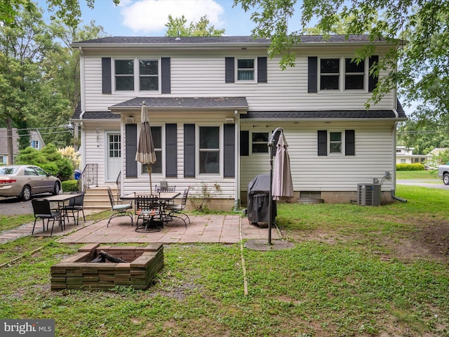 rear view of property featuring a patio, a lawn, central AC unit, and an outdoor fire pit