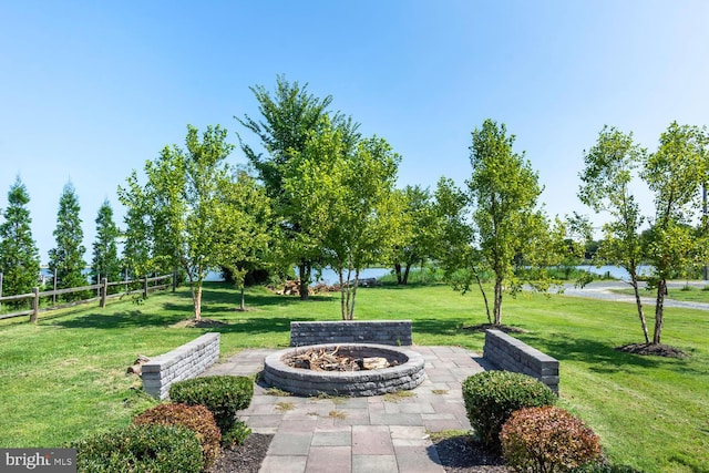 view of home's community with a patio, a water view, a yard, and an outdoor fire pit