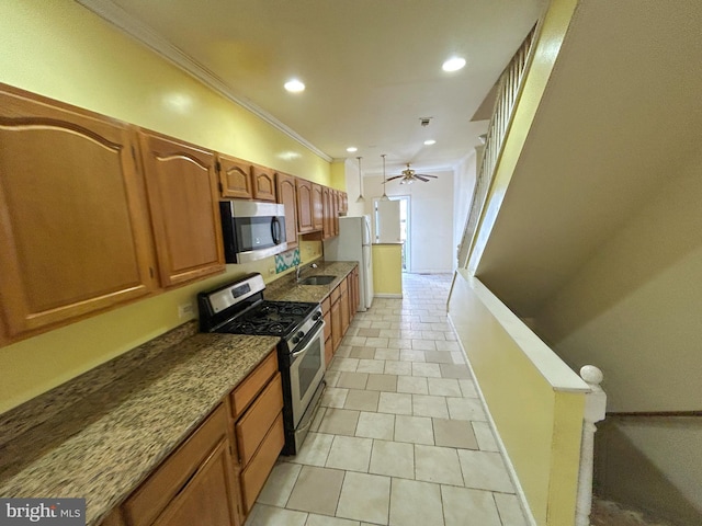 kitchen with appliances with stainless steel finishes, sink, ornamental molding, ceiling fan, and light stone counters