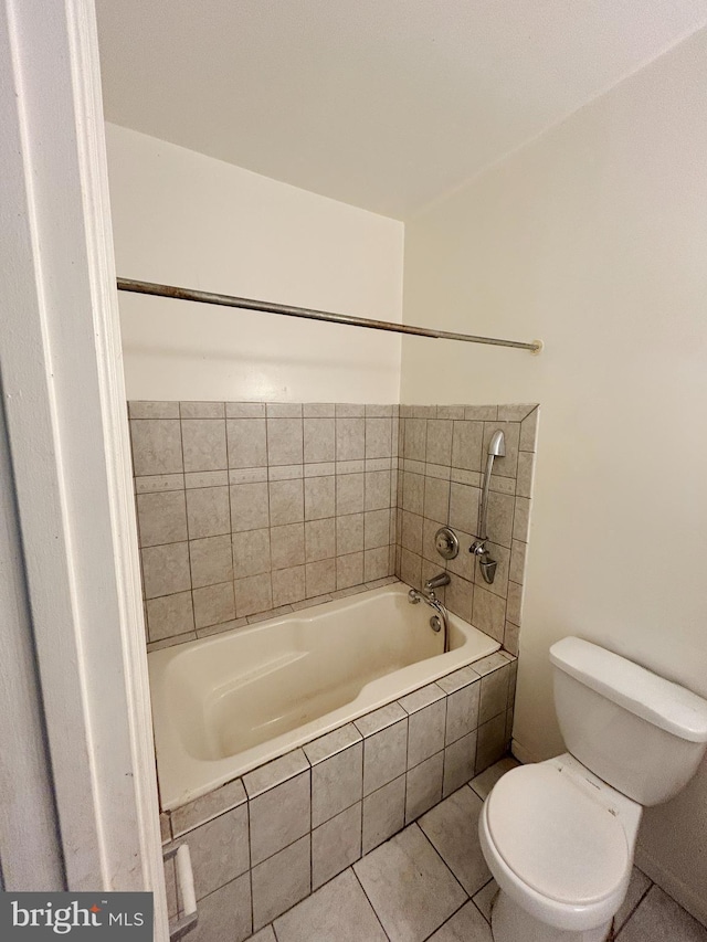 bathroom with tiled bath, tile patterned floors, and toilet