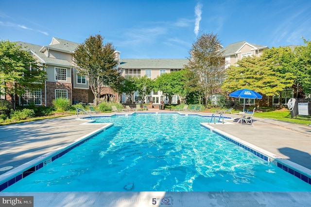 community pool with a patio and fence