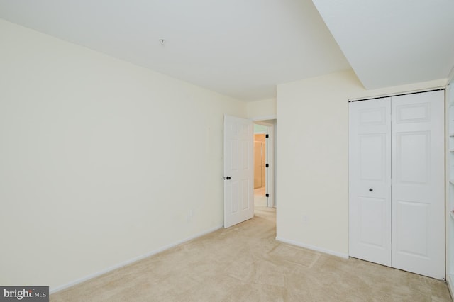 unfurnished bedroom featuring baseboards, a closet, and light colored carpet