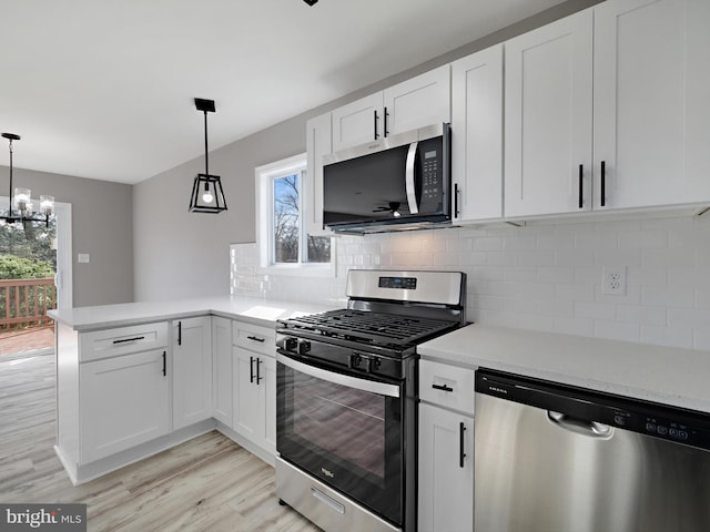 kitchen with decorative light fixtures, stainless steel appliances, kitchen peninsula, and white cabinets