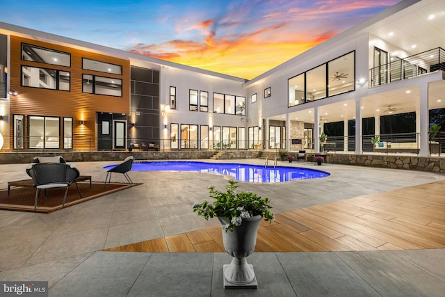 pool at dusk with a patio area