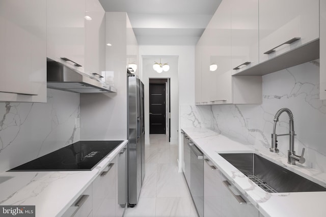 kitchen with white cabinetry, stainless steel appliances, light stone countertops, and sink