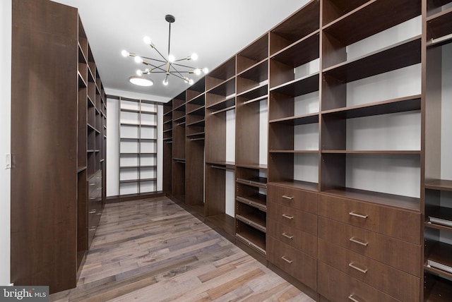 spacious closet with a notable chandelier and light hardwood / wood-style floors