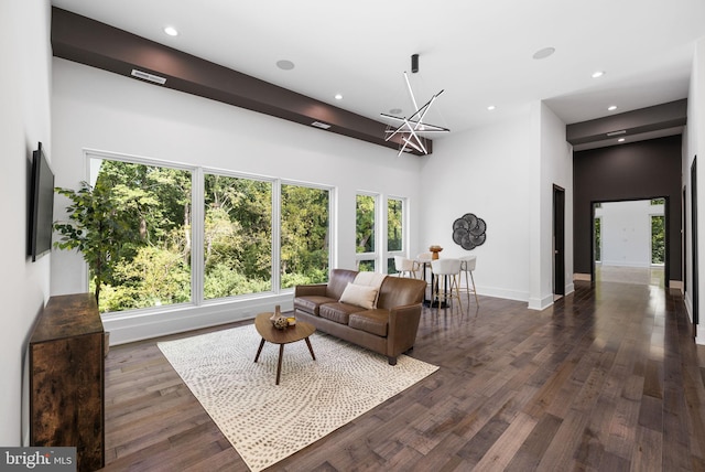 living room featuring a towering ceiling, dark hardwood / wood-style floors, and a chandelier