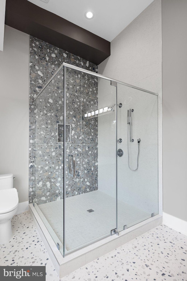 bathroom with toilet, tile patterned flooring, and a shower with door