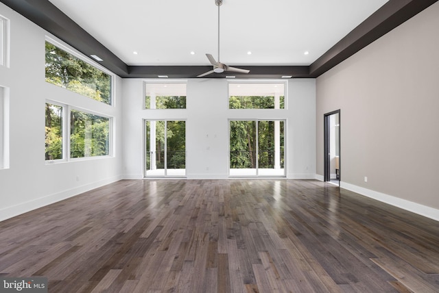 unfurnished living room with dark hardwood / wood-style flooring, a towering ceiling, and ceiling fan