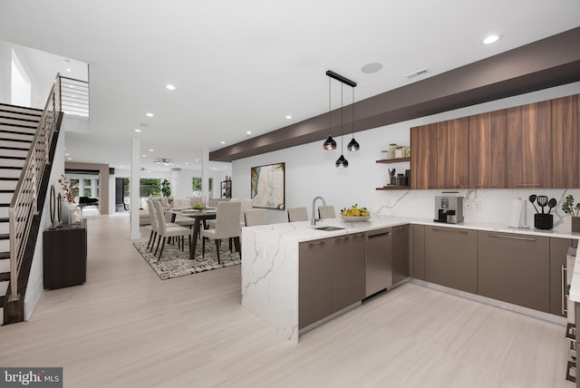 kitchen featuring sink, hanging light fixtures, stainless steel dishwasher, light stone counters, and kitchen peninsula