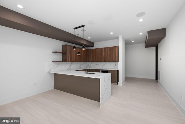 kitchen featuring sink, decorative backsplash, hanging light fixtures, kitchen peninsula, and light stone countertops