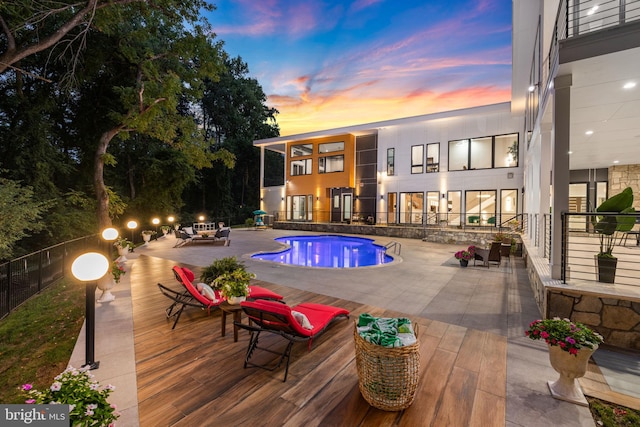 pool at dusk featuring a patio and a fire pit