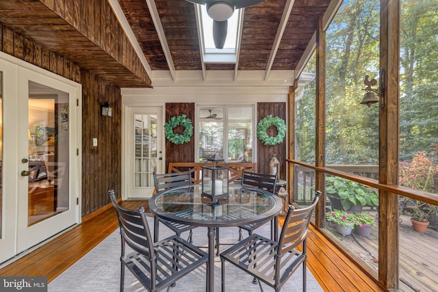 sunroom / solarium with a skylight, beam ceiling, and wood ceiling