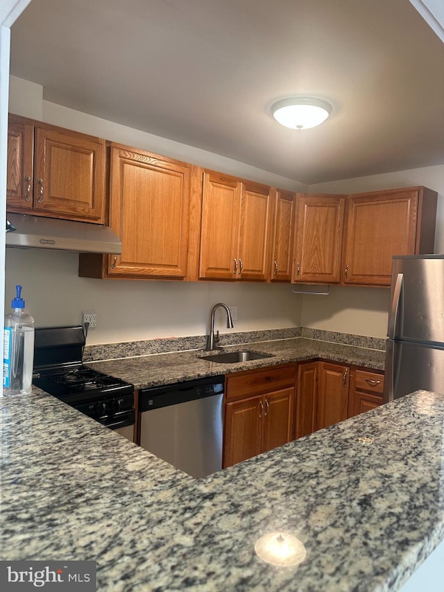 kitchen with sink, stainless steel appliances, and dark stone counters