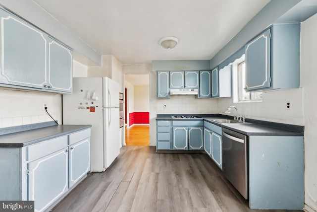 kitchen featuring light wood-type flooring, appliances with stainless steel finishes, sink, and backsplash