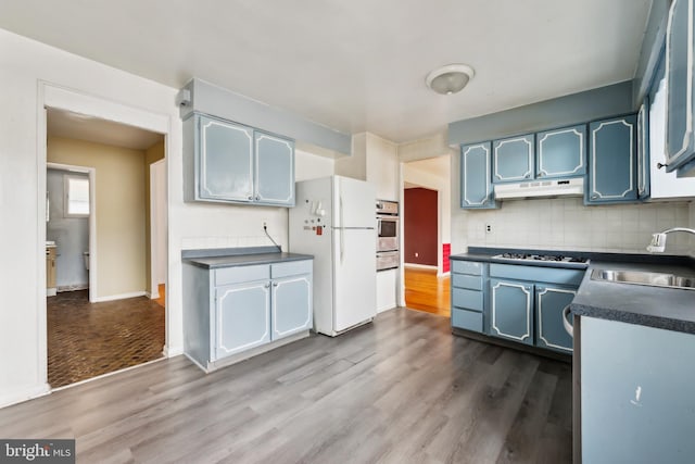 kitchen with stainless steel oven, dark hardwood / wood-style floors, sink, and white fridge