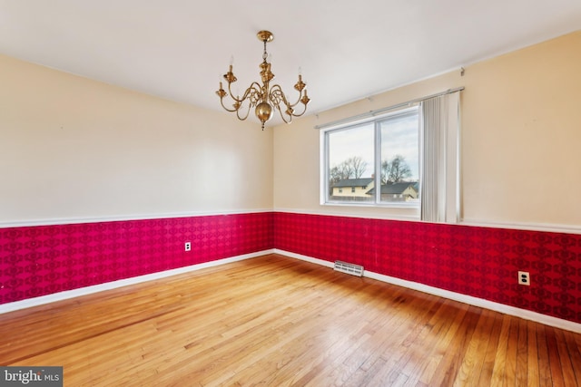 unfurnished room with wood-type flooring and a notable chandelier