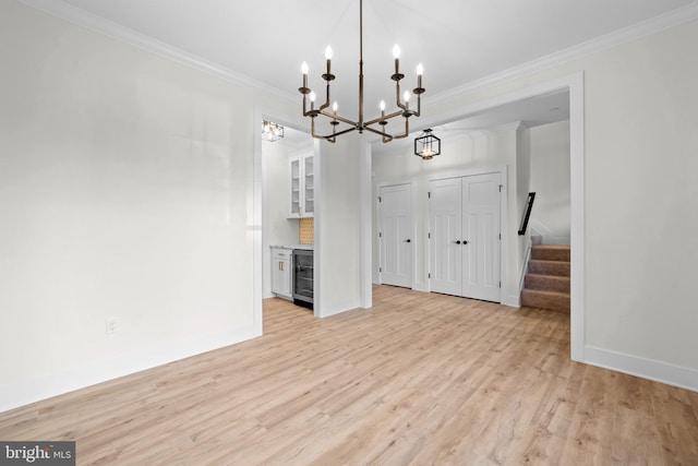 unfurnished dining area with wine cooler, crown molding, and light hardwood / wood-style floors