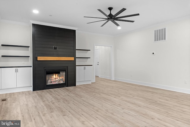 unfurnished living room featuring crown molding, a large fireplace, ceiling fan, and light wood-type flooring