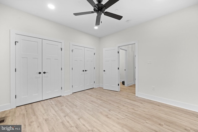 unfurnished bedroom with ceiling fan, light wood-type flooring, and two closets