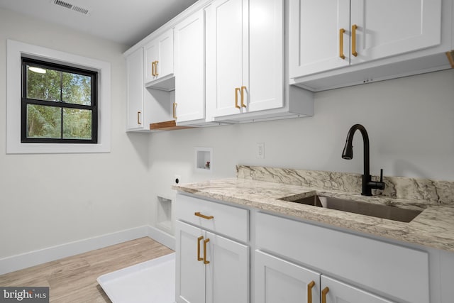 clothes washing area with sink, light hardwood / wood-style flooring, hookup for a washing machine, cabinets, and hookup for an electric dryer