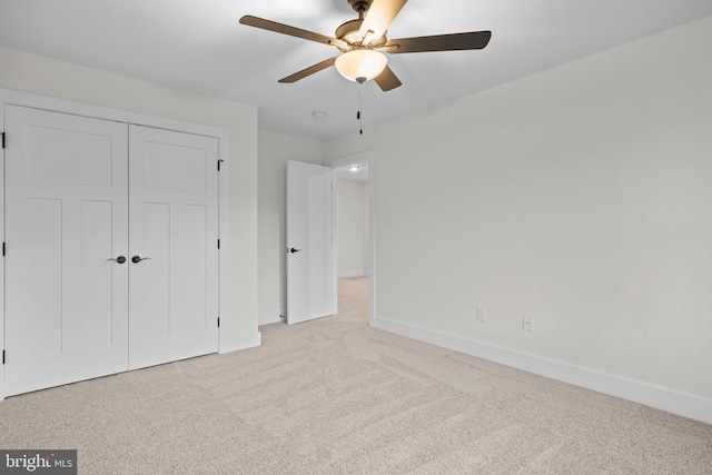 unfurnished bedroom with ceiling fan, light colored carpet, and a closet