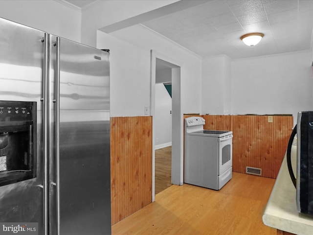 kitchen featuring wood walls, crown molding, light hardwood / wood-style flooring, white electric stove, and stainless steel fridge