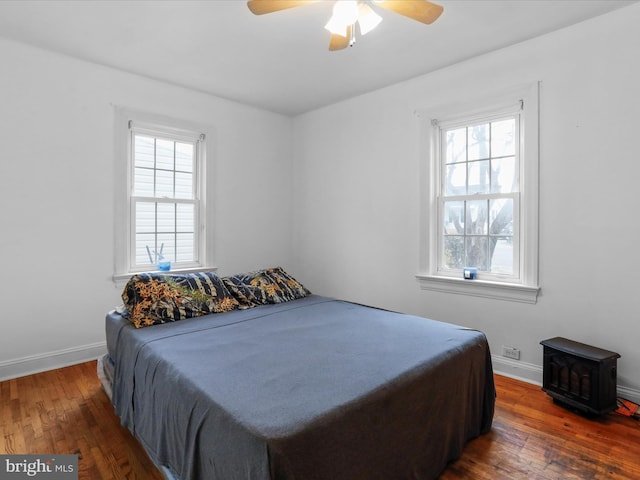 bedroom with multiple windows, dark wood-type flooring, and ceiling fan