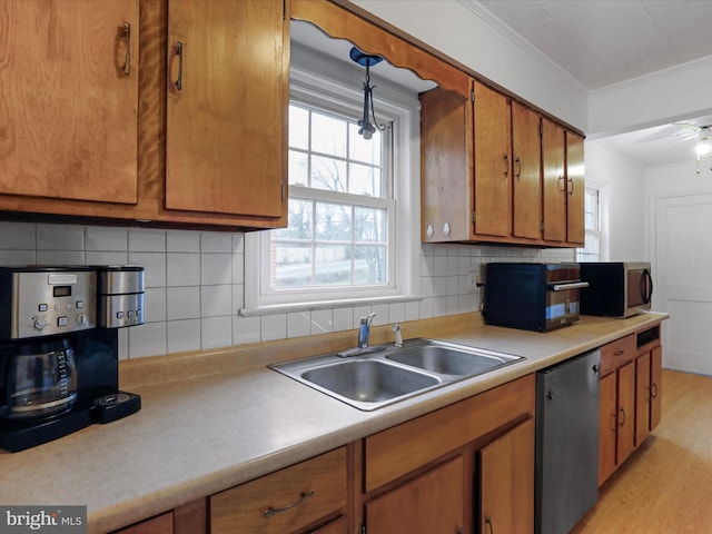 kitchen with sink, hanging light fixtures, stainless steel appliances, ornamental molding, and light wood-type flooring