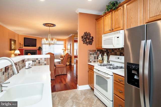 kitchen with pendant lighting, sink, crown molding, white appliances, and tasteful backsplash