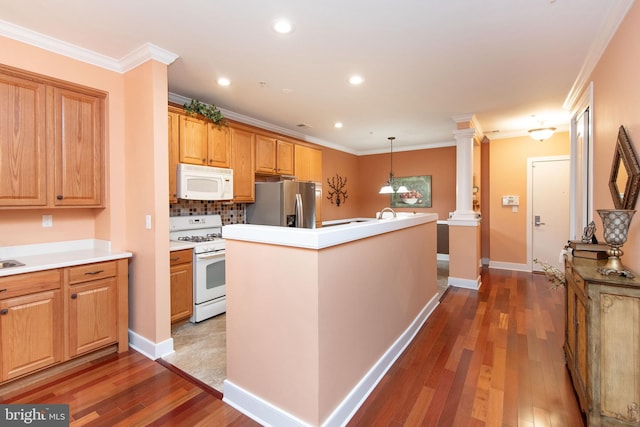 kitchen with pendant lighting, white appliances, ornamental molding, and decorative columns