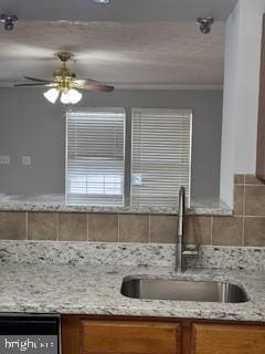 kitchen featuring sink, backsplash, light stone countertops, and ceiling fan