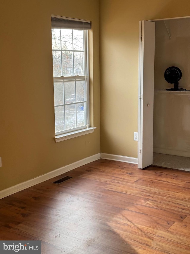 unfurnished bedroom with multiple windows, light hardwood / wood-style flooring, and a closet