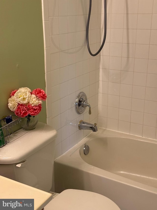 bathroom featuring toilet and tiled shower / bath