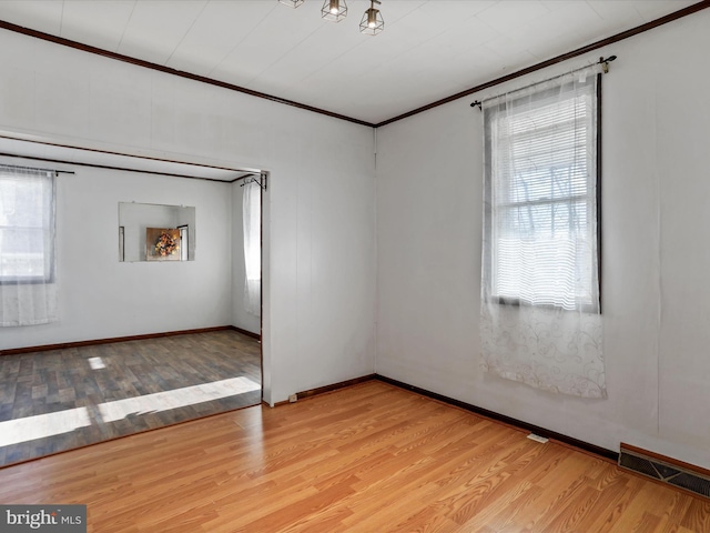 spare room with ornamental molding and light hardwood / wood-style floors