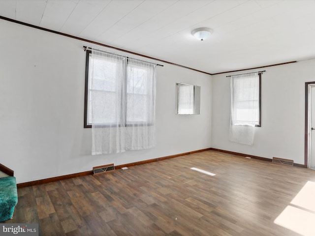 spare room featuring dark hardwood / wood-style flooring, plenty of natural light, and ornamental molding