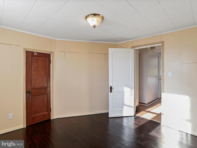 empty room with hardwood / wood-style flooring and crown molding