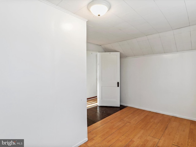 empty room with wood-type flooring and vaulted ceiling